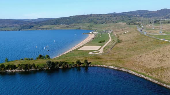 people enjoying the lake beach and its gardens, sailboats sailing on a sunny afternoon. Drone shooti