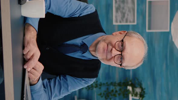 Vertical Video Senior Man Looking at Camera Smiling Sitting in Workplace at Desk