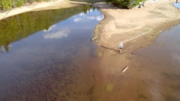 Woman with her pet dog walking near river coast on a sunny day 4k