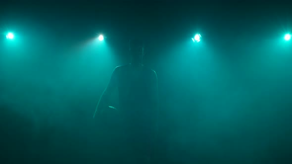 Out of Darkness and Smoke Silhouette of Guy Walking Straight Into Camera with Basket Ball in His