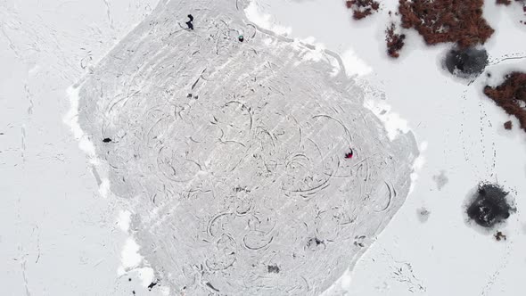 People ice skating on the ice lake. Top aerial view