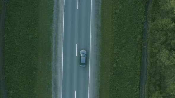 Aerial View of a Car Driving on the Road in a Field