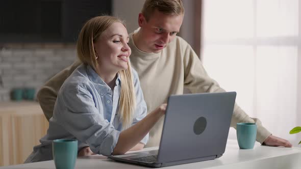 Couple 30s Wife and Husband in Kitchen Using Laptop Enjoy Eshopping Remotely Planning Future