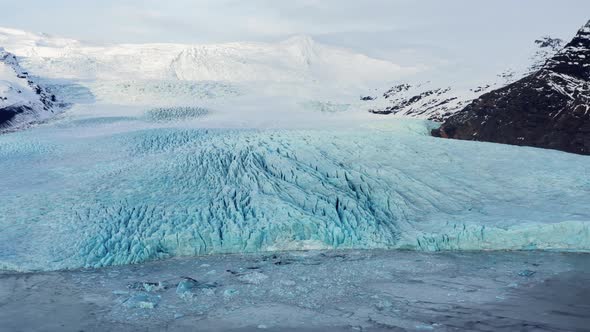 Drone Towards Glacier Amongst Snow Covered Mountains