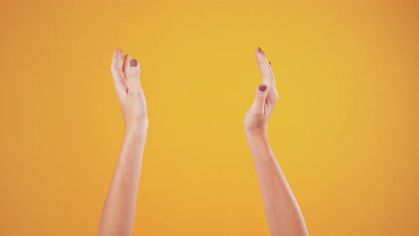 Hands of Female Clapping Over Orange Studio Background