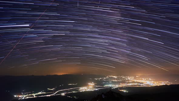 Star Trails In Night Sky. Illuminated night city under the stars, 4K