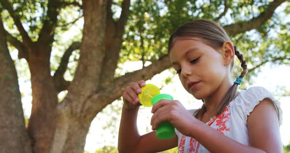 Girl blowing bubbles through bubble wand