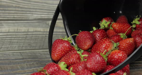 Strawberries in a Small Black Bucket on the Wooden Table - Close Up