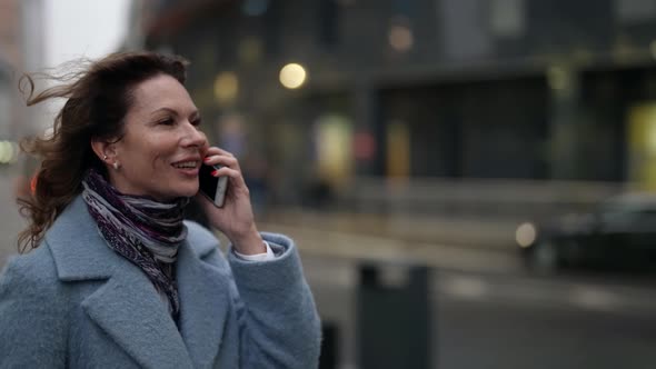 Woman is Calling By Mobile Phone When Walking in Downtown in Autumn or Winter Day