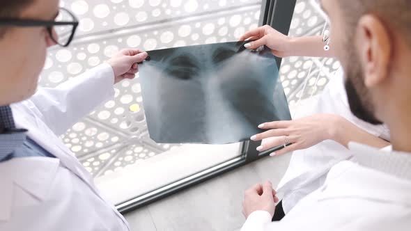 Doctors in Protective Clothing Looking at Xray Pictures of the Lungs