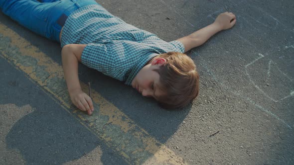 School Boy Laying on the Park Pathway. Autistic Boy Playing with Wooden Stick on the Ground.