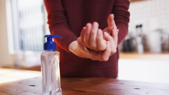 Mid section of woman sanitizing her hands at home