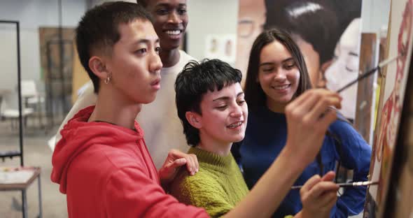 Multiracial students painting together inside art classroom at university