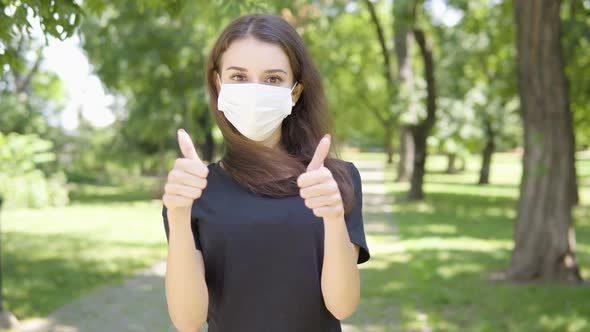 A Young Turkish Woman in a Face Mask Shows Double Thumbs Up To the Camera and Nods