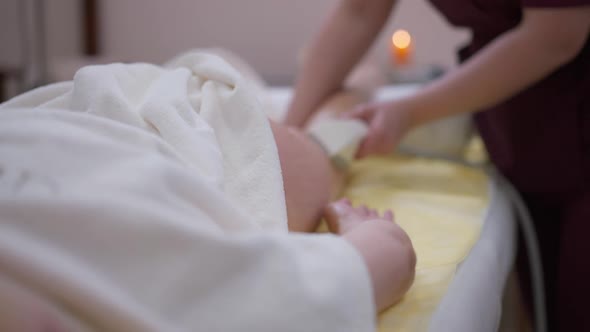 Closeup White Towel with Blurred Masseur Massaging Client Thigh and Buttock in Slow Motion at