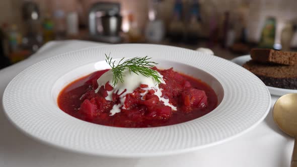 Plate of red beetroot soup borsch rotates on table. Traditional Ukraine food
