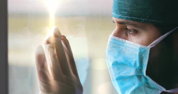 Tired Doctor or Nurse is Watching from a Window