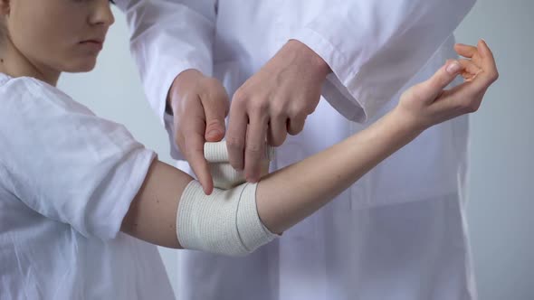Doctor Bandaging Injured Patient Hand, First Aid for Sprain in Trauma Clinic