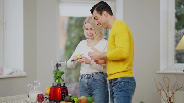 Side View of Happy Loving Interracial Couple Cutting Fruits for Smoothie and Talking