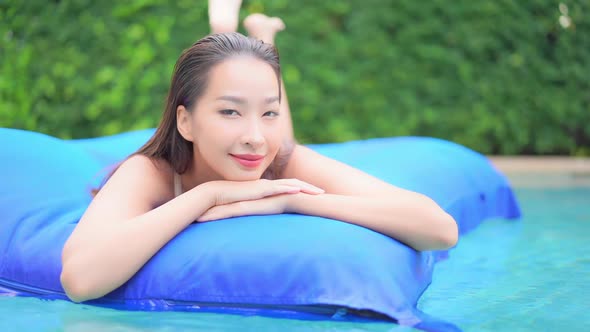 Portrait of  Beautiful Sexy Exotic Woman on Air Mattress in Swimming Pool on Tropical Holiday, Looki