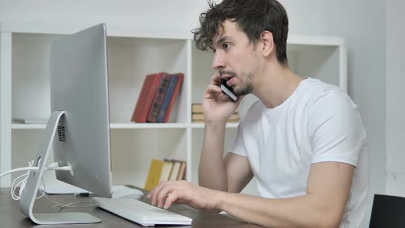 Creative Young Man Talking on Phone and Discussing Work