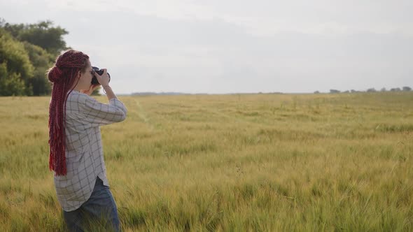 Girl Stands in a Wheat and Take Some Photos of Fields