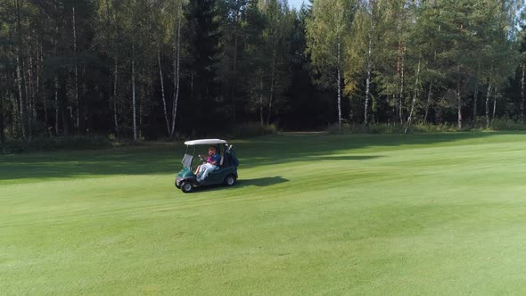 Summer Sunny Day Aerial View of Golf Course in Forest Area Golf Club Man and Woman Ride in Electric