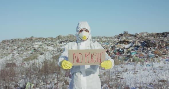 Portrait of Man Wore in Protective Suit Show Protest Sign "No Plastic" at Camera