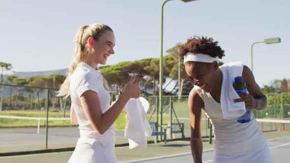 Video of happy diverse female tennis players talking and resting after match