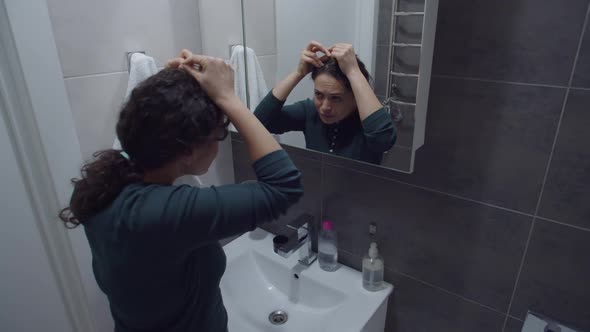 Concerned Woman Noticing Hair Problem Looking at Mirror in Bathroom