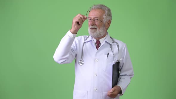 Handsome Senior Bearded Man Doctor Against Green Background