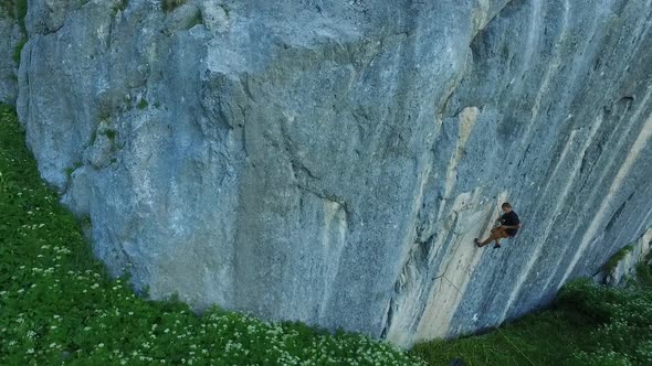 Aerial drone view of a man rock climbing up a mountain.