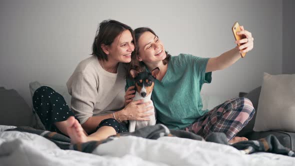 A Lesbian Couple Taking a Selfie with Their Cute Basenji Dog on a Smartphone