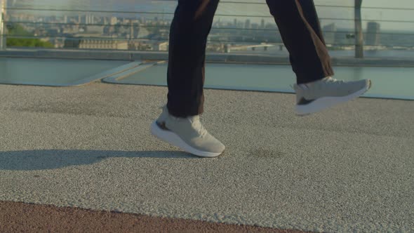 Closeup of Male Legs in Sports Shoes Exercising with Skipping Rope Outdoors