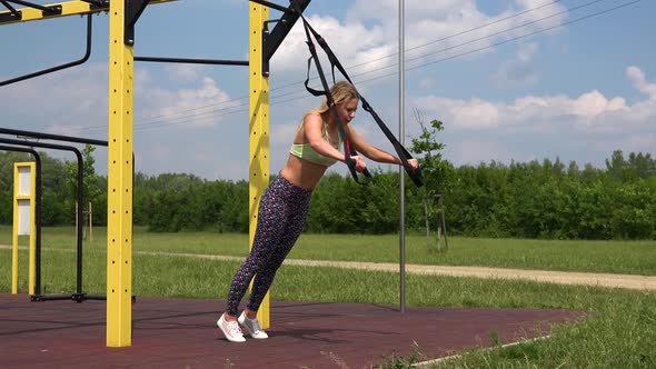 A Fit Beautiful Woman Does Inclined Push-ups at an Outdoor Gym