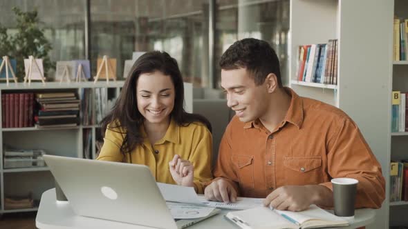 Two Young Casual Business People \ Couple Using Computer Discussing Financial Reports in the Office