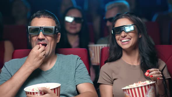 Smiling Hispanic Couple Watching Comedy Film in 3D Glasses Eating Popcorn Having Positive Emotion