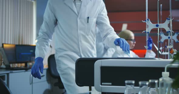 Scientist Loading Vials Into a Testing Machine alt