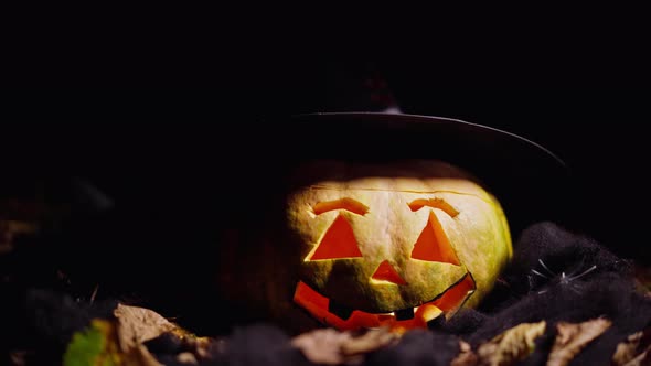 Closeup Scary Jackolantern in Witch Hat with Lightnings Flashing Fast in Darkness