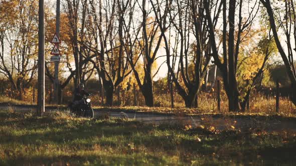 Man Riding Old Custom Caferacer Motorcycle on Country Road at Autumn Sunny Day