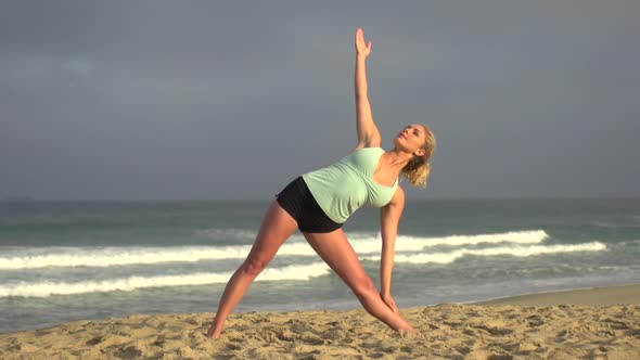 A young attractive woman doing yoga on the beach.