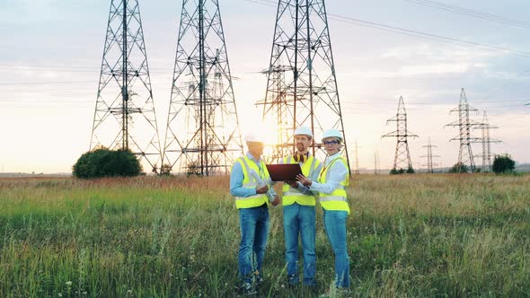 Field with Transmission Towers and a Group of Engineers. Energy Saving, Energy Efficiency Concept