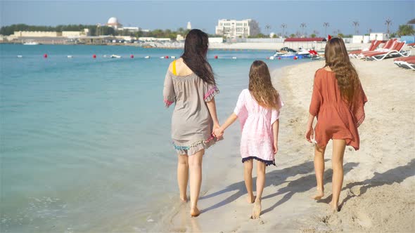 Adorable Little Girls and Young Mother on White Beach