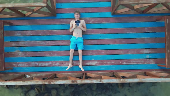 Man with Drone Controller Making Selfie From Drone Camera Lying on Pier