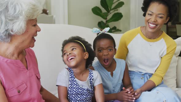 Portrait of happy african american grandmother with adult daughter and granddaughters in living room