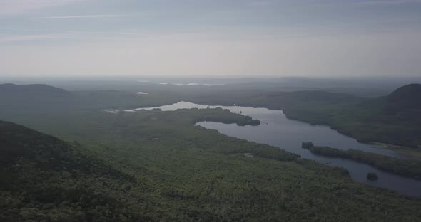 Aerial Drone Shot Panning Across Beautiful Lake Amongst Endless Forests