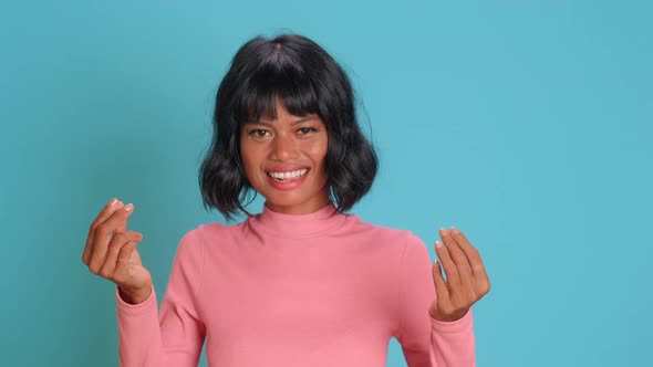 Young Woman Makes Money Gesture Has Idea of Big Profit Against Blue Background