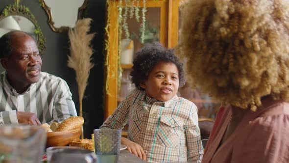 African American Boy Chatting with Parents at Family Dinner