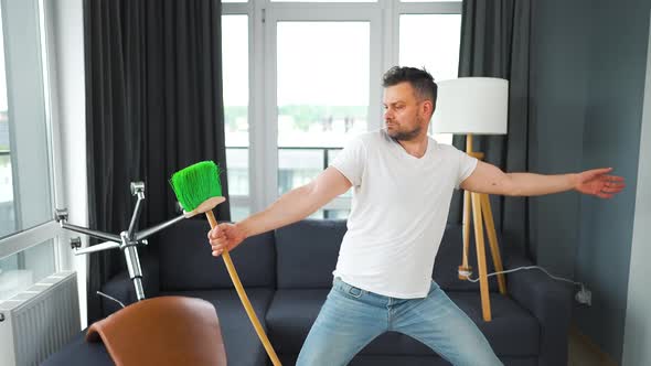 Man Cleaning the House and Having Fun Dancing with a Broom