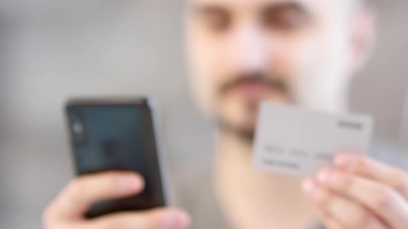 Man Paying Online with Smartphone and Bank Card